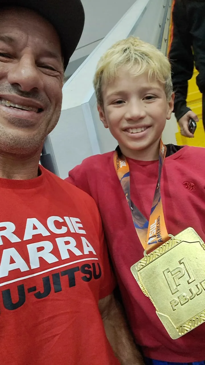 Jovem praticante celebra uma medalha acompanhado de um adulto
